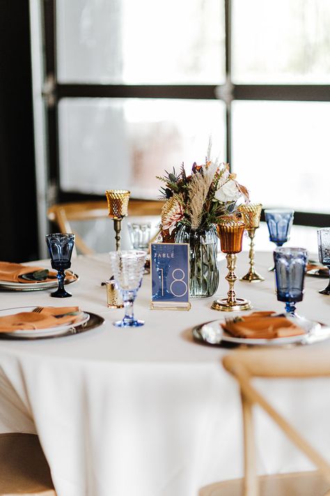 Wedding Reception Tablescape with Unique Blue Debutante Goblet Glassware and Dried Boho Centerpieces |Fall Wedding Design Inspiration Navy Blue And Copper Wedding Table Decor, Navy Terracotta Wedding Table, Terracotta And Navy Centerpieces, Blue And Orange Wedding Table Settings, Navy Fall Wedding Decor, Terracotta And Blue Wedding Decor, Navy Blue Fall Wedding Centerpieces, Terracotta And Blue Wedding Palette, Terracotta And Blue Bouquet