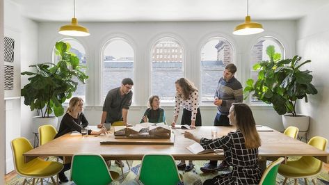 Architects at MASS Design collaborating at conference table lined with green and yellow Eames Shell Chairs. Large Conference Table, Office Lifestyle, Mass Design, Meeting Room Table, Corporate Values, Collaborative Workspace, Green Desk, Office Meeting Room, Green Office