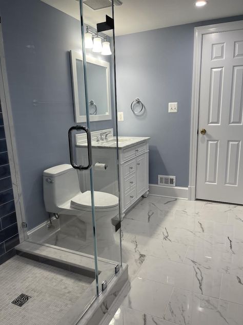 Blue-Gray Bathroom Reno! We chose a new vanity with drawers to help with better organization. We installed a 12 x 24 porcelain tile on the floor from Marble Systems to make the space appear larger. The shower is completely new with 1 x 1 tumbled marble on floor, new shower door and glass panel with polished chrome hinges, and beautiful navy blue handmade tiles on the wall. A new Toto toilet that's easy to keep clean. The bathroom was complete with a coat of new paint! Custom Showers, White Marble Shower, Grey Marble Floor, Clean The Bathroom, Vanity With Drawers, Marble Shower Tile, Light Blue Bathroom, Marble Bathroom Floor, Vintage Style Bathroom