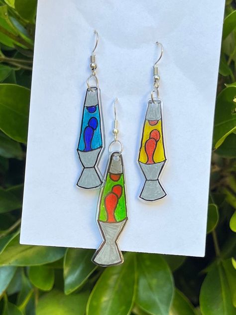 These super cute earrings are lava lamps made out of shrinky dinks. They come in 3 different color options. They are lightweight and perfect for any fun outfit! Lava Lamp Earrings, Shrink Plastic Ideas Diy, Shrinks Dink Ideas, Rhinestoned Things, Cute Shrinky Dink Ideas, Shrinky Dink Ideas Templates, Juniper Art, Woodstock Theme, Shrink Earrings