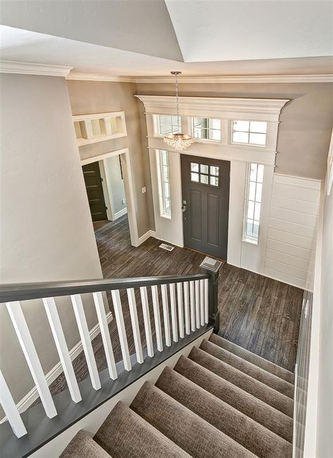 Entryway with gray stair rail and white balusters. Gray door and tall door  casing in Grey Stair Railing, Window Above Door, Banister Ideas, Staircase Banister, Entry Chandelier, Landing Ideas, Gray Stairs, Escalier Design, French Industrial