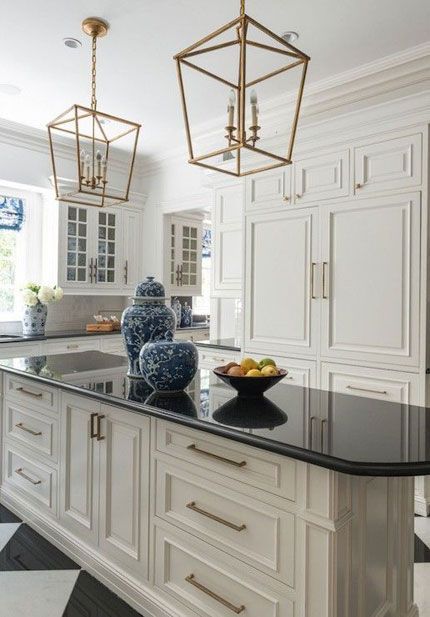 One kitchen trend that’s gaining momentum as we head into the new year is white cabinets with black countertops, commonly referred to as the ‘tuxedo kitchen.’ Not only is the contrast of white against black dramatic and alluring, it’s practical. Black countertops hide stains and smudges, while white cabinets are a timeless and functional choice for any kitchen design style. Cage Pendant Light Over Island, White Kitchen Floor, Antique White Kitchen Cabinets, Cream Kitchen Cabinets, Antique White Kitchen, Pendant Lantern, Chandelier Vintage, Black Countertops, Farmhouse Kitchen Island