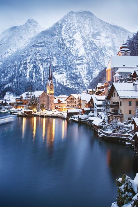 Snow-topped Austrian village with houses and church on the shores of Lake Hallstatt in the evening light. Snow-covered mountains loom behind. Aesthetic Trip, Austria Winter, Hallstatt Austria, Luxury Ski, Holiday Places, Beautiful Sights, Travel List, Travel Sites, Christmas Vacation