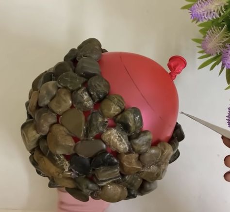 Woman glues stones together around balloon to make cutest stone flower pots Concrete Balloon Bowls, Pebble Bowl Diy, Rock Bowls Projects, Rock Flower Beds With Potted Plants Garden Ideas, Rock Bowl Diy, Crafts With Rocks, Diy Decorative Balls, Balloon Diy Crafts, Rock Ornaments