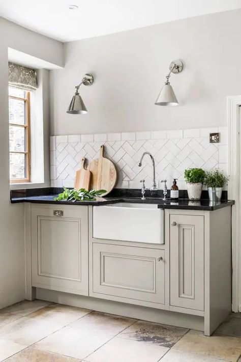 a greige farmhouse kitchen with shaker cabinets, a white tile backsplash, a black countertop and lovely metallic sconces Greige Kitchen, Black Kitchen Countertops, Black Countertop, White Tile Backsplash, Black Countertops, Shaker Style Kitchens, Tudor House, Kitchen Redo, How To Design