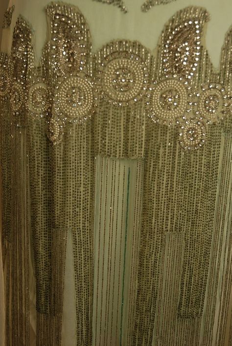 JEWELED DRESS with BEADED FRINGE, 1920's. White chiffon with deep "U" neckline front and back trimmed with a wide band of pearl, rhinestone and crystal bead medallions, wide jeweled hip band with graduated long beaded fringe, chiffon flower and drape at left shoulder, attached aqua underdress possibly not original. -Detail Front 3 1920s Textiles, 1920s Beading, Lucile Dress, 1920 Dresses, Vinatge Dress, Art Deco Embroidery, Mom Prom, 1920s Theme, Period Fashion