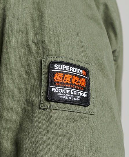 Superdry men's Classic rookie jacket. This casual jacket features a zip and popper fastening, four external pockets, popper fastened cuffs, drawstring adjustable waist, and a single internal pocket. Finished with popper fastened epaulettes, zip detailing on the collar, a Superdry logo badge on one sleeve, and a Superdry logo patch on one pocket. Superdry Label Design, Superdry Coat, Superdry Label, Superdry Shirts Men, Superdry Tshirt, Superdry Logo, Superdry Mens, Logo Badge, Green Jacket