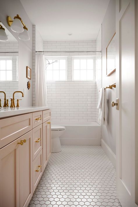 This Seattle bathroom is anything but void of personality! We took this all white guest bath and gave it a modern upgrade with a pop of pink on the vanity, which compliments the gold hardware perfectly! The white hexagon floor tile adds playful texture, while classic subway tiles make the shower feel timeless! Chevron Tile Floor Bathroom, Classic Hexagon Tile Bathroom, Pink Penny Tile Bathroom, Honeycomb Tiles Bathroom, Pink Bathroom Tile, White Hexagon Floor, White Hexagon Tile Bathroom, Chevron Tiles Floor, Hexagon Floor Tile