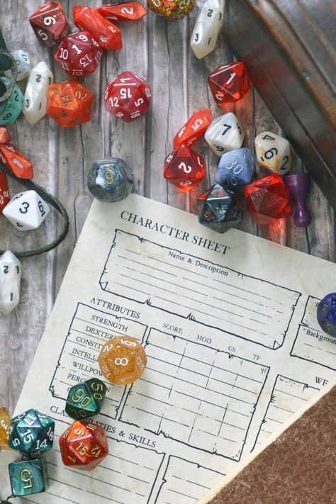 overhead shot of a table with Dungeons & Dragons character sheets, colourful 20-sided role-playing gaming dice and game pieces scattered around the paper. Fantasy Name Generator, D Name, Dm Screen, Dungeons And Dragons Dice, Embrace The Chaos, Location Inspiration, Dungeons Dragons, Name Generator, Fantasy Setting