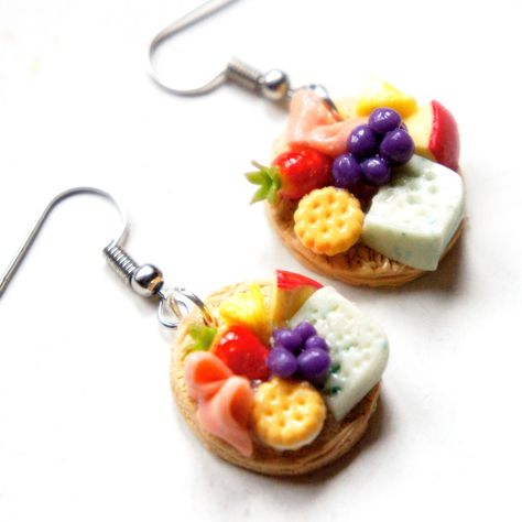 These earrings feature a pair of miniature wooden boards of fruits, meats, cheeses, and cookies made from polymer clay. The board measures about 2 cm in diameter and hangs from a silver tone hook. Silly Earrings, Assorted Fruits, Crazy Earrings, Weird Jewelry, Mini Stuff, Handmade Clay Jewelry, Clay Stuff, Food Earrings, Funky Earrings