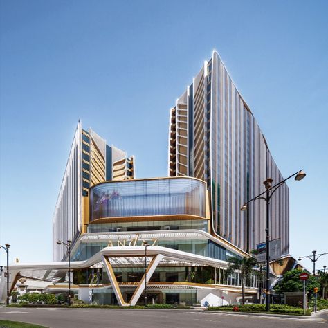 The façade of the podium is a dynamic composition of fluid white forms, providing a striking contrast to the functional rectangular form of the building. Gold and white canopies, that wrap the podium, provide a sense of movement and energy, accentuating the entrances of the arena, exhibition space, and hotel. The façade is further enhanced by integrated, programmable LED lighting and large-scale screens, which enliven the architecture and create a distinctive new presence on the Macau skyline. Convention Center Design, Mall Architecture, Urban Living Room, Macau China, Green Terrace, Architecture Practice, International Architecture, White Canopy, The Two Towers