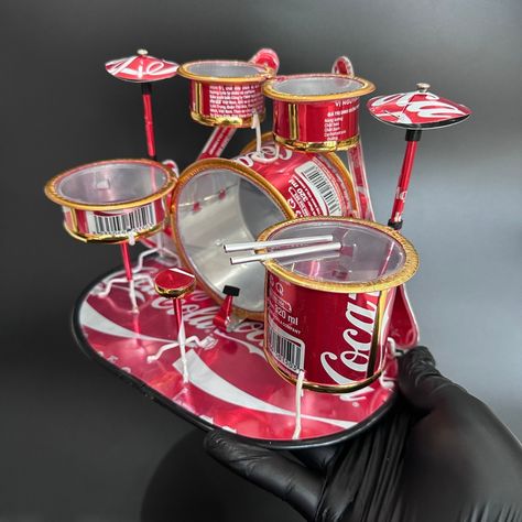 Handcrafted Coca-Cola Can Drum Set Model – Unique Recycled Metal Art for Music Lovers & Collectors This handcrafted drum set model is a unique piece of art made entirely from recycled soda cans. Measuring approximately 9.05 inches in length, 6.29 inches in width, and 5.90 inches in height, this miniature drum set is a stunning example of upcycled creativity. Each component is meticulously shaped and assembled by skilled artisans in Vietnam, turning discarded cans into a beautiful and functio... Art For Music Lovers, Soda Can Art, Recycled Tin Cans, Drums Art, Recycled Metal Art, Coca Cola Can, Recycled Tin, Junk Art, Metal Projects