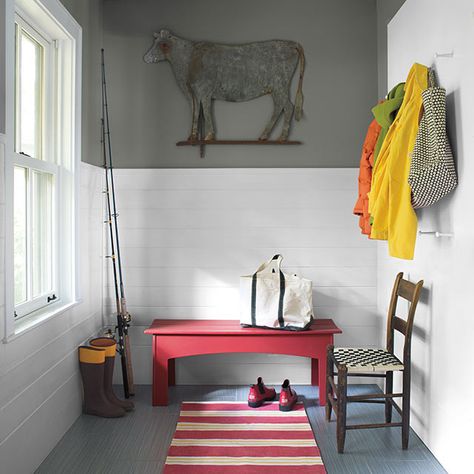 A mudroom with white wainscoting halfway up a gray wall featuring a red bench, red and white striped rug, and jackets hung on the wall. Mudroom Paint Color Ideas, Mudroom Paint Colors, Amherst Gray, Mudroom Paint, Mudroom Paint Color, Red Bench, Gloss Cabinets, White Wainscoting, Mudroom Design