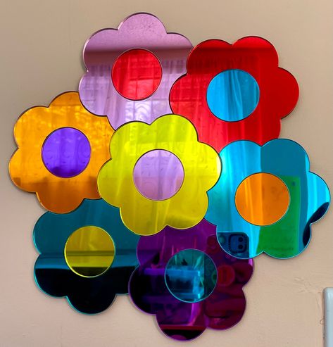 Rainbow Daisy Acrylic MirrorMeasures approx 30cm at its widest.And 29cm approx at its narrowest.Approx 6mm thick, fixes with command strips or other securing tapes. Please ensure that you use what is suitable for your walls. It must also be applied to flat walls.Weighs approx 270g.It can be turned round any way you prefer it.Using coloured mirror acrylic, laser cut, put together and backed with Plywood or MDF, whichever is readily available.There are 7 daisies, with the colours Baby pink, red, o Daisy Mirror, Coloured Mirror, Rainbow Mirror, Rainbow Daisy, Mirror Wall Hanging, Acrylic Photo Frames, Colored Mirror, Art Mid Century, Mirror Acrylic