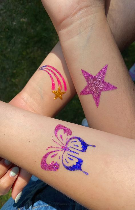 this pin shows three glitter tattoos on a group of peoples' arms. One tattoo is a pink star, one is a blue and pink butterfly, the last is a shooting star with a gold star and pink ombre lines. Glitter Tattoo Temporary, Glitter Tattoo Designs, Glitter Tattoo Summer, Diy Glitter Tattoos, Glitter Temporary Tattoos, Temporary Glitter Tattoo, Glitter Tattoo Aesthetic, Glitter Tattoo Permanent, Shimmer Tattoos