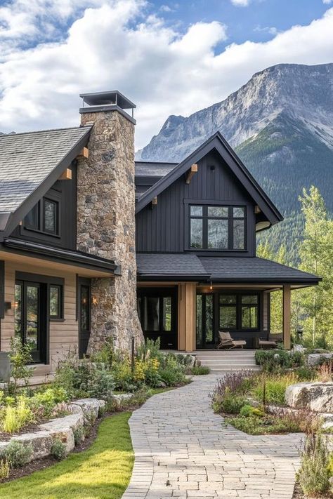 Modern cottage style mountain house facade with taupe siding charred wood accents stone chimney front yard with cobblestone pathway imposing mountain in the background. Check out the trending exterior colors for modern mountain houses that blend harmoniously with natural surroundings while adding a touch of contemporary flair. Jasper House Exterior, Dark Siding House Exterior Colors With Stone, Modern House Lots Of Windows, Craftsmen House Exteriors, Mountain Ranch Home Exterior, Mountain Modern Landscaping, Rustic House Design Exterior, Mountain Exterior House Colors, Modern Cabin Exterior Design