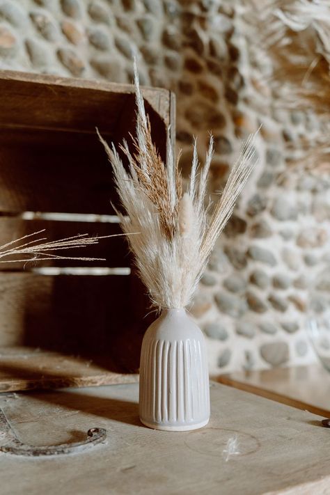 This shows a close up of a off white bud vase, with dried flowers in it. In the background is a wooden crate. Vase With Dried Flowers, Ceramic Bud Vases, Barn Photography, Vase Collection, Vases And Vessels, Rustic Barn, Different Shapes, Bud Vases, Antique Style