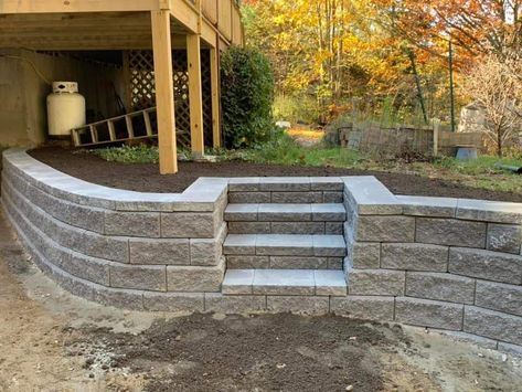 Retaining Wall Outdoor Kitchen, Curved Retaining Wall With Steps, Patio On Sloped Yard Backyards, Stone Retaining Wall With Steps, Concrete Patio Ideas With Retaining Wall, Sink Holes In Yard, Sloped Backyard Patio Ideas, Landscape Design Retaining Wall, Retaining Wall Steps Sloped Backyard