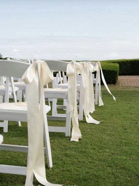 Decorate White Folding Chairs Wedding, White Plastic Chairs Wedding Decoration, Bow Pew Decorations Wedding, Tulle Wedding Aisle, Wedding Ceremony Bows On Chairs, Bow Chairs Wedding, Wedding Isles Outdoor Elegant, Bow Aisle Decor, Simple Outdoor Isle Wedding Decor