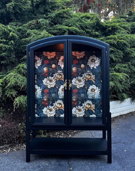 Description: Unique vintage China Cabinet, Bar, Bookcase  features black custom finish, (2) glass doors with glass side panels, designer wallpaper backing in a floral motif in blacks, brown, cream and rust, brass decorative "floral" pulls, interior lighting with custom legs and shelf. One-of-a-kind re-imagined piece perfect for a variety of decor.  Would make a wonderful china/ liquor cabinet or fill with your favorite books and display items in tour dining room, living room or a special additio Cabinet Glass Doors Display, Diy Display Cabinet Makeover, Refurbished Glass Cabinet, Curio Cabinet Wallpaper, China Cabinet With Wallpaper Back, Vintage Cabinet Decor, Ikea Glass Door Cabinet, Antique Glass Cabinet, Bar Bookcase