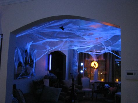 Halloween Decorations: buy dollar store spider webs, hang all over, light with black lights Halloween Kickback Decorations, Spiders Hanging From Ceiling Halloween, Web Halloween Decor, Hanging Halloween Lights, Lighting For Halloween Party, Lighted Halloween Decorations, Halloween Ceiling Decoration, Spider Web Ceiling Decoration, Halloween Venue Decorations