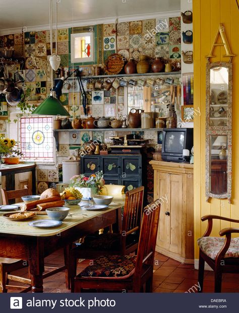 Download this stock image: Old pine table and chairs in cluttered cottage kitchen with narrow mirror on the wall - DAEBRA from Alamy's library of millions of high resolution stock photos, illustrations and vectors. Pine Table And Chairs, Narrow Mirror, Maximalist Kitchen, Boho Style Kitchen, Cottage Core Kitchen, Kitchen Clutter, Eclectic Kitchen, Pine Table, Mirror On The Wall