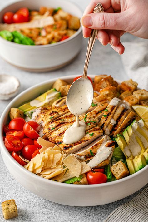 A spoon drizzling freshly-made dressing over a grilled chicken Caesar salad packed with refreshing flavors: hearts of romaine, sliced avocado, ripe cherry tomatoes, shaved parmesan cheese, mini sourdough croutons and fresh lemon wedges. Caesar Salad Photography, Caesar Salad Recipes, Dressing Made With Greek Yogurt, Creamy Caesar Salad, Salad Photography, Grilled Chicken Caesar, Grilled Chicken Strips, Photography Restaurant, Grilled Chicken Caesar Salad