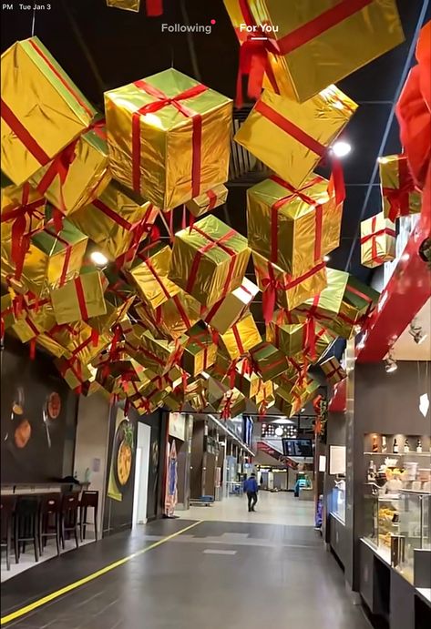 Hanging Christmas Presents From Ceiling, Presents Hanging From Ceiling, Warehouse Christmas Decor, Santa's Toy Factory Decorations, Christmas Ceiling Installation, Walk Through Christmas Display, Hanging Presents From Ceiling, Christmas Decor Restaurant Ideas, Christmas Decor Hotel