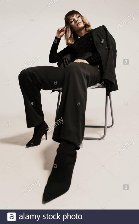 Download this stock image: Portrait beautiful woman with attitude sitting on a chair wearing black clothes posing on white background looking at the camera - 2BGECA9 from Alamy's library of millions of high resolution stock photos, illustrations and vectors. Sitting Down On Chair Poses, Woman Sitting On A Chair Pose Reference, Person Sitting In Chair Pose, Pose Reference Photo Sitting Chair, Poses On The Chair, High Fashion Chair Poses, Power Sitting Pose, Woman Sitting In Chair Pose, Powerful Sitting Pose