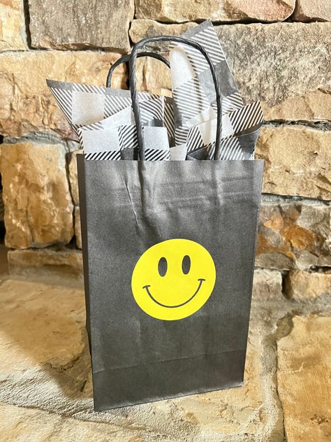 "Smiley Face Favor Bags! Black bags adorned with a yellow smiley fave, perfect for gift bags, party favors, shopping...the possibilities are endless! Made from 50% recycled paper and high quality vinyl! This listing is for: --ONE 5.25\" x 3.5\" x 8.25\" Black Favor Bag with yellow custom vinyl sticker and one sheet of black and white checkered tissue paper *Made in the USA  Please note color may vary in person compared to what you see on your computer monitor/phone. Refunds and exchanges of unopened, unused and undamaged product may be accepted within 30 days of order received. Shipping is nonrefundable and buyer is responsible for return shipping.  Thanks so much for looking!" Smiley Face Favors, One Happy Dude Party Favors, Smiley Face Gifts, One Happy Dude, Cool Dude, Custom Vinyl Stickers, Skate Party, Wrapping Party, Baby Shower Favor