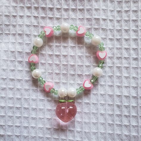 This peach blossom bracelet was inspired by the reason I look forward to summer every year - peaches! It features a delightful combination of green and pink, with pearls and a peach charm! Materials: - 0.7 mm elastic string - green beads - pink heart beads - pearl beads - pink peach charm Bracelet Aesthetic Beads, Beaded Bracelet Aesthetic, Cute Beaded Bracelet, Peach Bracelet, Bracelet Aesthetic, Bracelets Pearl, Peach Necklace, Pink Pearl Bracelet, Elastic Bracelets