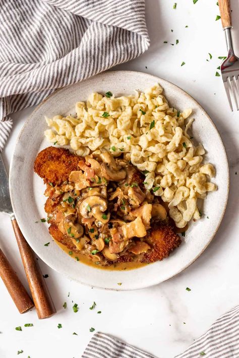 Pork Schnitzel with bacon mushroom gravy is an easy 30-minute weeknight dinner that is a family favorite! The pan-fried pork chops are crisp and golden on the outside, but tender enough to cut with a fork. This easy German jägerschnitzel recipe is perfect with mashed potatoes, egg noodles, späetzle, or rice and a veggie on the side. #schnitzel #jagerschnitzel #porkschnitzel #german #austrian #porkchops #crisp #breaded #sauce #gravy #bacon #best Jagerschnitzel Recipe, Jaegerschnitzel Recipe, German Recipes Dinner, German Noodles, Pork Schnitzel Recipe, German Dinner, German Schnitzel, Schnitzel Recipe, Pan Fried Pork Chops