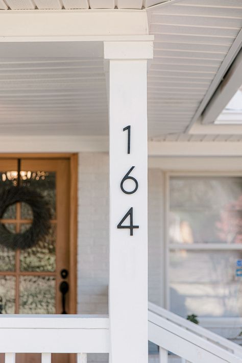 Front patio with white wood columns and railing. Stained front door and wood decking to cover concrete slab. Covering Concrete Steps, 50s House Exterior, Columns On Front Porch, Gray Brick House Exterior, Painting Wood White, White Railing, Grey Brick Houses, Pure White Sherwin Williams, Patio Covering