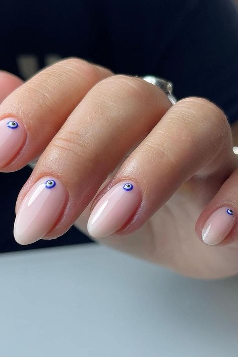 Almond-shaped nails in an elegant nude ombre finish, each accented with a single dainty blue evil eye charm near the cuticle. The minimalist design exudes sophistication with a touch of protective charm. Perfect for those who appreciate subtle details.✨  // Photo Credit: Instagram @beautyhaven_byjodie Xs Almond Nails, Evil Eye Nail Ideas, Rock Hairstyle, Evil Eye Nail, Evil Eye Nails, Eye Nail Art, Short Almond Nails, Squoval Nails, Nails Nude