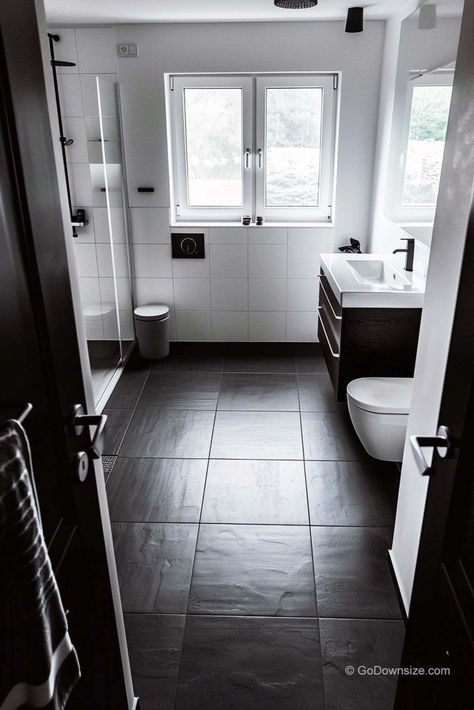 This bathroom is all about keeping things sleek and simple. The crisp white walls are the perfect contrast to the dark flooring. Bathroom Black Floor White Walls, Small Bathroom Dark Floor, White Square Tile Bathroom, Bathrooms With Black Floors, Dark Tile Bathroom Floor, Bathroom Black Floor, Bathroom Dark Floor, Dark Bathroom Floor Tile, Dark Floor Bathroom