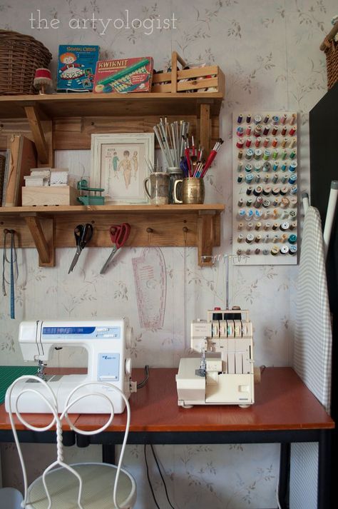 A desk sits against a wall with a sewing machine and serger on top of it. Two wall shelves are hung above with baskets of supplies and vintage sewing patterns and supplies displayed on them. Floating Shelves Sewing Room, Sewing Desk Storage, Sewing Wall Storage, Farmhouse Sewing Room Ideas, Sewing Setup Small Space, Vintage Sewing Desk, Sewing Room Organisation, Cottage Sewing Room, Sewing Room Vintage