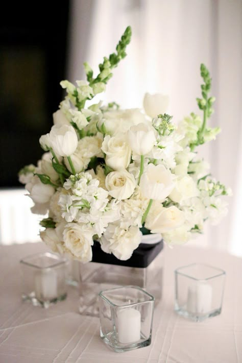 All-white centerpieces of tulips, roses, carnations and stock were surrounded by square votives for a modern, yet romantic look White Wedding Flower Arrangements, Christmas Floral Arrangements Diy, White Wedding Flowers Centerpieces, White Flower Centerpieces, White Wedding Centerpieces, White Floral Centerpieces, White Floral Arrangements, White Flower Arrangements, White Centerpiece