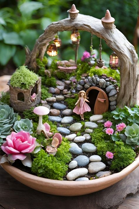 A miniature fairy garden with a moss-covered house, glowing lanterns, pink flowers, and a fairy figurine surrounded by lush greenery and rocks in a bowl-shaped container. Backyard Fairy Garden, Fairy Garden Lantern, Enchanting Backyard, Fairy Garden Ideas, Garden Lantern, Garden Lanterns, Tiny Plants, Stone Path, Fairy Figurines