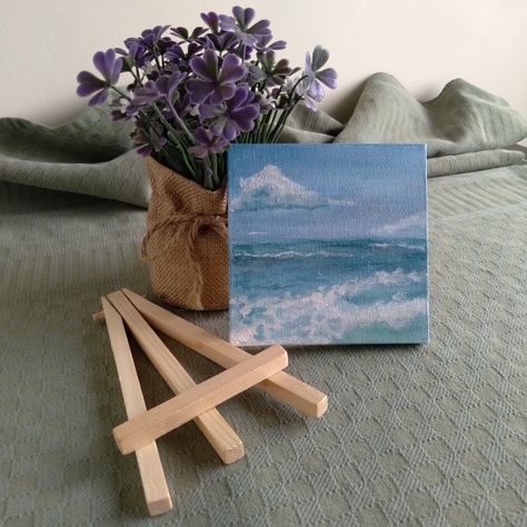 A picture of a miniature canvas painting of the seaside balancing on a fake purple plant beside a miniature wooden easel on a dark green cloth Funny Painting Idea, Painting Waves, Blue Paintings, Painted Wooden Boxes, Canvas Background, Picture Painting, Funny Paintings, Wooden Canvas, Beauty Art Drawings