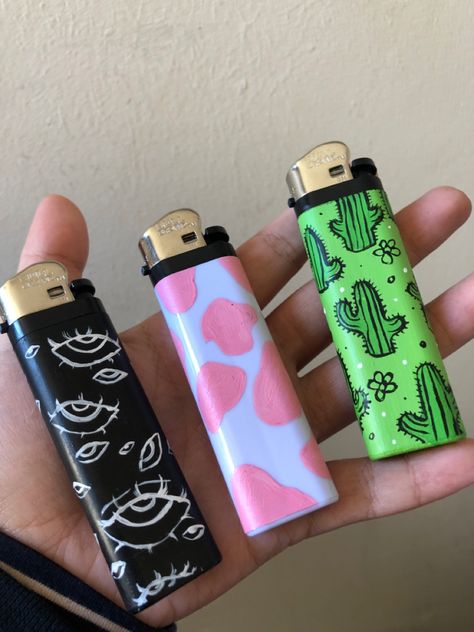 Acrylic paint designs: creepy eyes, pink cow print, cute green cacti Aesthetic Lighter Drawing, Painting Lighters Diy, Lighter Ideas Diy, Lighter Art Diy, Painting On Lighter, Painted Lighters Aesthetic, Diy Lighter Painting, Cool Lighter Aesthetic, Painted Lighter Aesthetic