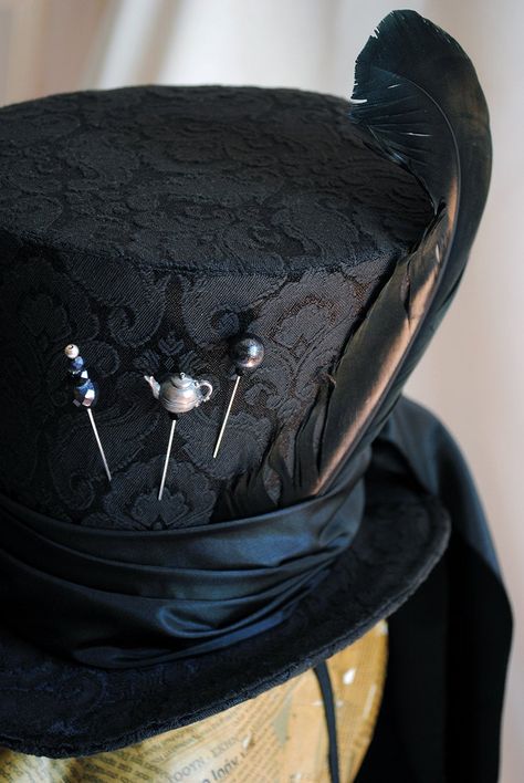 "A total black Mad Hatter ladies top hat to match the darkest Alice in Wonderland inspired costumes! This glorious hat is covered with a wonderful black brocade fabric. It is embellished with a long black taffeta train that goes around the brim and falls luxuriously at the back. The hat wouldn't be complete without some \"mad hatter\" details! A black duck feather, three unique hat pins and the signature 10/6 tag! Cause around here it's always tea-time! Fully lined with satin. Attaches with a th How To Make Mad Hatter Hat, Gothic Top Hat, Top Hat Character Design, Top Hat Aesthetic, Mad Hatter Inspired Outfit, Gothic Mad Hatter, Mad Hatter Costume Female, Mad Hatter Outfit, Army Dreamers