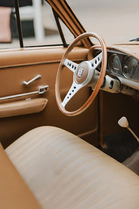 The interior of a classic car featuring a pristine tan leather interior, showcasing a vintage steering wheel and dashboard. Tan Leather Car Interior, Vintage Car Interior Aesthetic, Car Interior Aesthetic, Vintage Car Interior, Leather Car Interior, Cream Car, 50s Cars, Color Aesthetic, Leather Car Seats