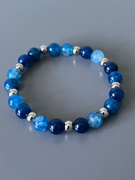 Beautiful blue dyed crackle agate gemstones bracelet will standout! Silver beads are stainless steel to prevent tarnishing. The beads are 8mm and silver beads are 6mm. Bracelet measures 7 inches. Beads are strung on durable 8mm elastic.  These are natural stones, so appearance of  beads on your bracelet may be different than pictured.  Please take care when putting in your bracelet to avoid excessive stretching. Roll bracelet onto wrist.  We hope you enjoy this one! Blue Gem Bracelet, Blue Bracelets Diy, Natural Bead Bracelets, Blue Bracelet Beads, Bracelets Stack, Blue Stone Bracelet, Stack Bracelets, Bracelets Handmade Diy, Blue Beaded Bracelets