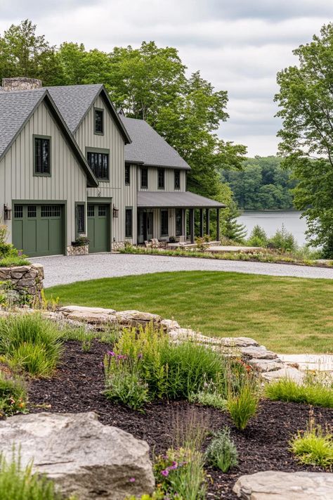 Wide angle view of a large modern farmhouse exterior in greyish pale green board and batten siding slightly darker sage green barn doors and window. Check out all of these dream farmhouses that will have you drooling with rural living fantasies and mooing with joy!