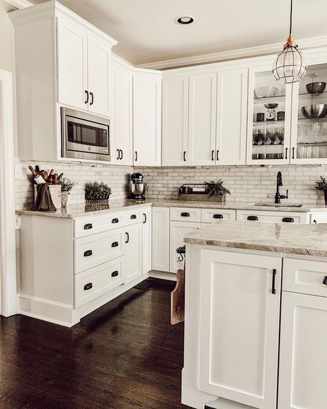 A brightly painted farmhouse kitchen with white cabinetry is paired with a beautiful multi-toned tile backsplash in gray, white, and off-white. The color variations within the counters match the shades within the backsplash perfectly. Small succulents add pops of organic color, and dark wood flooring accentuates the bright cabinetry. Backsplashes With White Cabinets, Kitchen Backsplashes With White Cabinets, Rustic Backsplash Ideas, White Kitchen Dark Floors, Backsplash Ideas For White Cabinets, Dark Kitchen Floors, White Kitchen Floor, Dark Brown Floor, Backsplash For White Cabinets