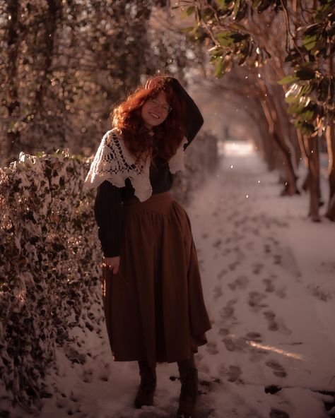 Red haired girl wearing a green waffle knit sweater tucked into a brown wool skirt with a “v” waist detail. She has on a crochet cream color shawl for added layering. She’s standing on a snowy pathway next to a hedge covered in snow. There are snowflakes catching the light beams. She’s smiling and holding her hair from being blown into her face by the wind. Winter Fashion Cottagecore, Cottagecore Outfits For Winter, Cottagecore Winter Dress, Cottagecore Rainy Day Outfit, Winter Outfits Cottagecore, Cottagecore Christmas Outfit, Little Women Inspired Outfit, Cottagecore Aesthetic Outfits Winter, Christmas Sweater Vest Outfit