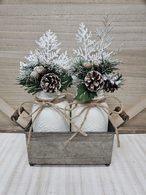 This farmhouse Christmas centerpiece is the perfect addition to your Christmas decor. This set includes 2 quart size Ball mason jars with jute bows, each hand painted in a winter white chalk paint and filled with a Christmas arrangement. Perfectly suited for a kitchen counter, table or mantle centerpiece! Makes a great gift too! The jars are nicely arranged in a galvanized metal tray with handles.  Set Arrangement (as pictured): (2) quart jars hand painted winter white (2) Christmas arrangements (2) jute bows (1) galvanized metal tray Jars are not dishwasher safe, and can not be submerged in water. They are easily cleaned using a damp cloth only.  Delivery is made by USPS. Tracking number provided.  Please do not hesitate to contact me if you have any questions.  Thank you for visiting my White Christmas Farmhouse Decor, Winter Season Decor, Farmhouse Winter Wedding, Winter Table Centerpieces Wedding, Winter Round Table Decor, Winter Baby Shower Table Centerpieces, Winter Console Table Decor, Winter Mason Jar Centerpieces, Small Christmas Centerpieces For Table