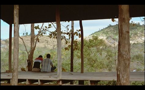 Tropical Malady Weerasethakul places the characters in the middle ground, facing away from us. Frames within frames and the guiding lines of the wooden structure help guide the eye to the two lovers. The idyllic Thai countryside in the extreme background completes the image. Frames Within Frames, Thai Countryside, Tropical Malady, Herd Of Elephants, Two Lovers, Western Film, Wooden Structure, Opening Credits, Film Grab