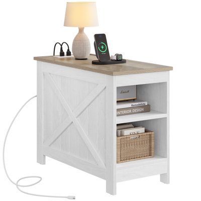 This side table outfits your living room with a handy platform for a lamp and charging electronics. Made from engineered wood, it comes in a two-tone finish of crisp white and natural brown. Crossbuck paneling on the sides lend a modern farmhouse vibe to your space. Two contained shelves are a great spot to tuck away books, magazines, and smaller storage bins. And the best part? There are two outlets and two USB ports to make sure your phone or tablet is fully charged and at the ready. | Laurel Table With Charging Station, Farmhouse Nightstand, Home Goods Furniture, White End Tables, Farmhouse End Tables, Narrow Side Table, Nightstand With Charging Station, Tall End Tables, Small Space Storage