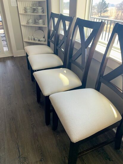 It’s DIY time again, and this time I’m sharing how I gave my dining area an easy and inexpensive makeover with this simple Chair Cover DIY using painter’s drop cloth.And by simple, I mean really simple. Can you operate a staple gun? Then you can completely recover your chairs in an hour or two, depending on how many chairs you have.BEFORE my Chair Cover DIYHere’s my “before” picture… I love our dining table because it’s big and can seat a lot of people. Here it is with 8 chairs, but… How To Make Dining Chair Seat Covers, How To Reapolstering Kitchen Chairs Diy, Recover Dining Chair Seats, Cover Chairs With Fabric Diy, How To Cover Chairs With Fabric, Diy Chair Back Covers, How To Recover Dining Room Chairs, Upholstering Dining Chairs Diy, Diy Dining Chairs Makeover